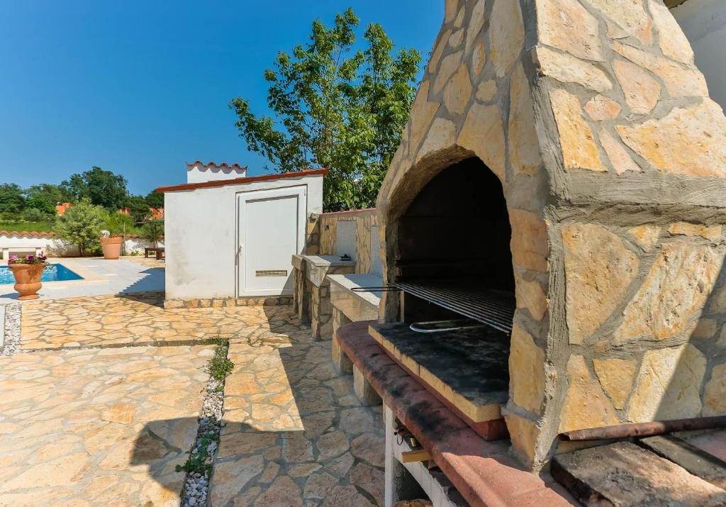 Veliki kameni roštilj s ognjištem uz bazen