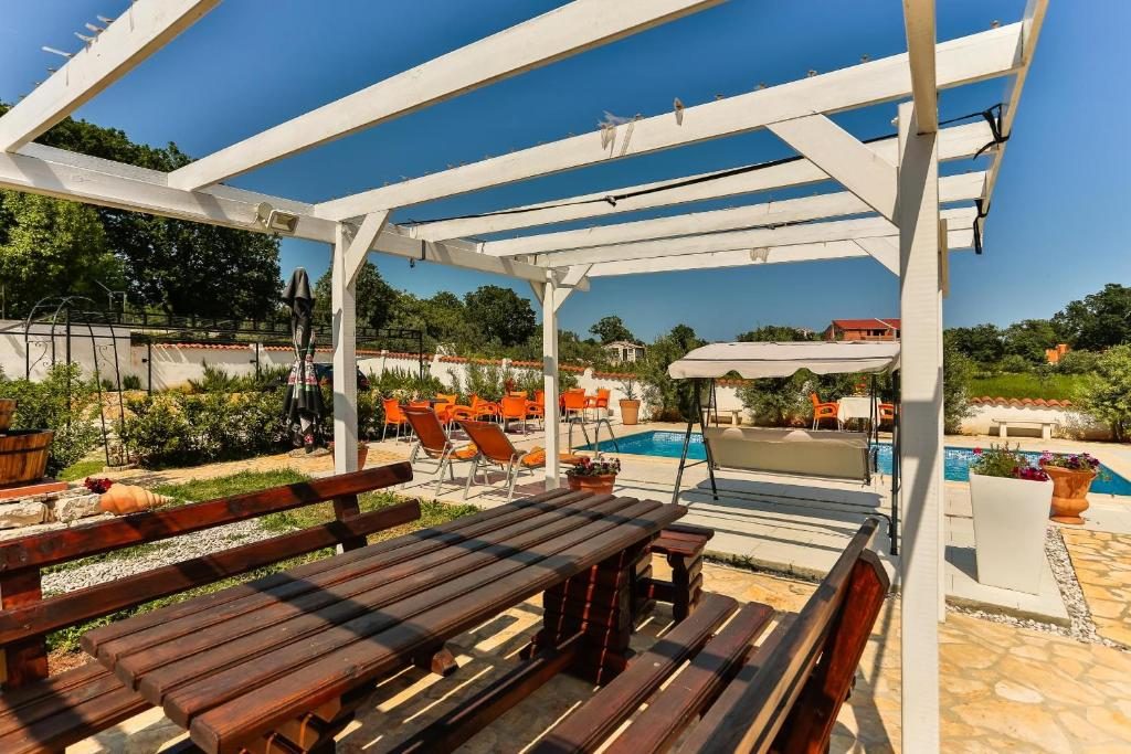 Pergola sa stolom i klupom uz bazen